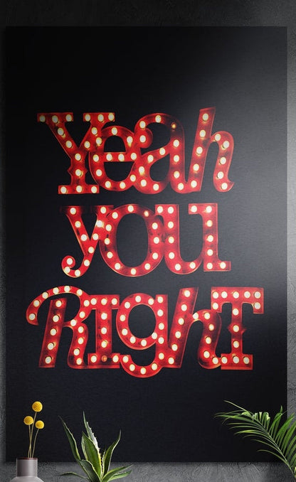 Red marquee lights brushed aluminum wall art on a dark textured wall behind a vase and potted plants