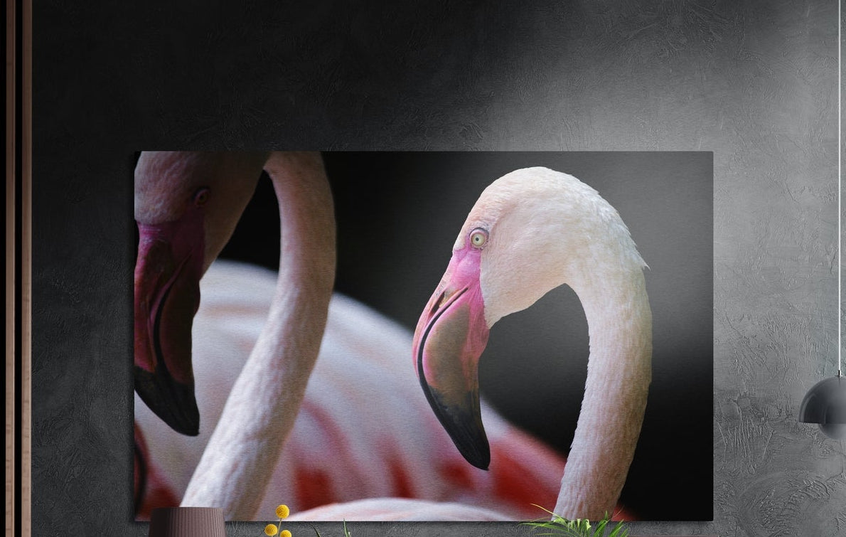 Pink flamingo close-up brushed aluminum wall art on a dark wall above a sideboard with yellow flowers
