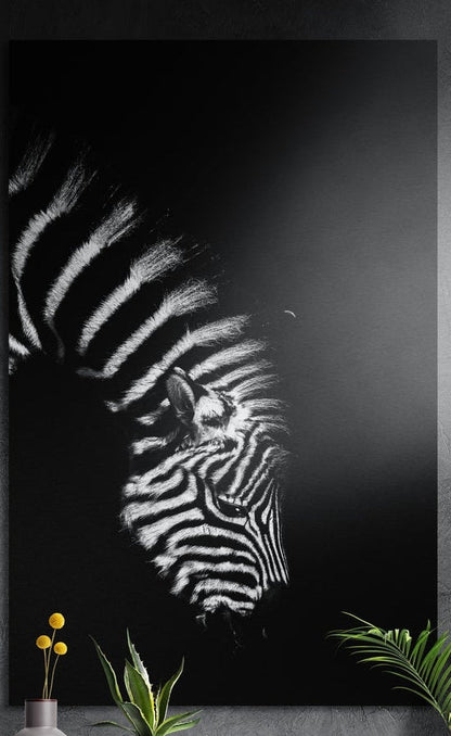 Black and white zebra profile brushed aluminum wall art on a dark wall behind yellow flowers and green plants