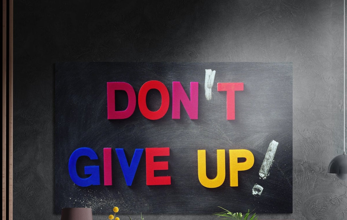 Don't give up colorful letters brushed aluminum wall art on a dark gray concrete wall