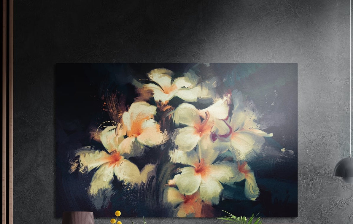 Cream frangipani flowers on dark blue brushed aluminum wall art on a dark textured wall above a lamp and yellow flowers