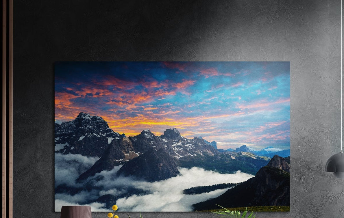 Mountain peaks brushed aluminum wall art on a dark gray wall above a sideboard with a vase and plants