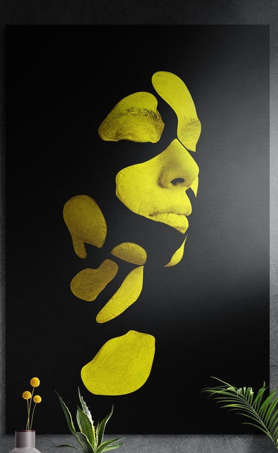 Yellow fragmented face brushed aluminum wall art on a dark textured wall above yellow flowers and potted plants