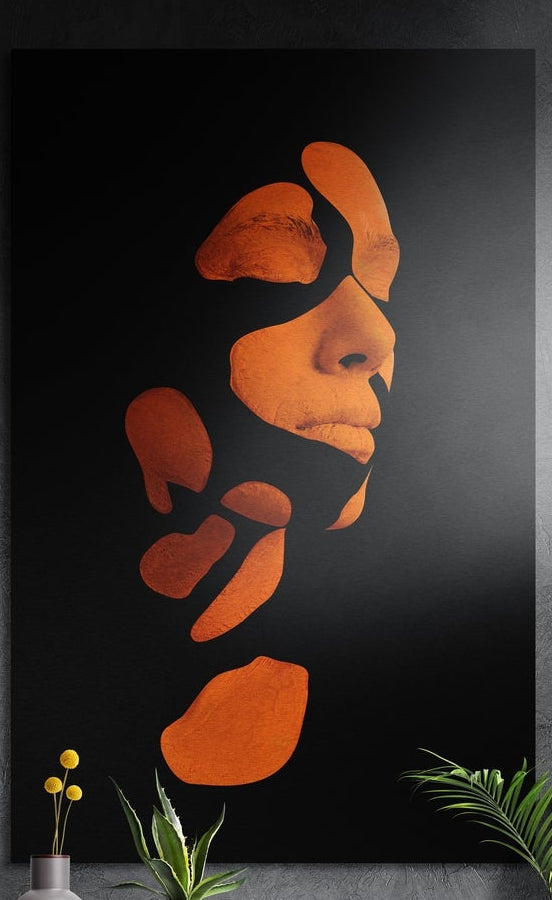Burnt orange shattered woman's face on a black background, brushed aluminum wall art on a dark wall above plants