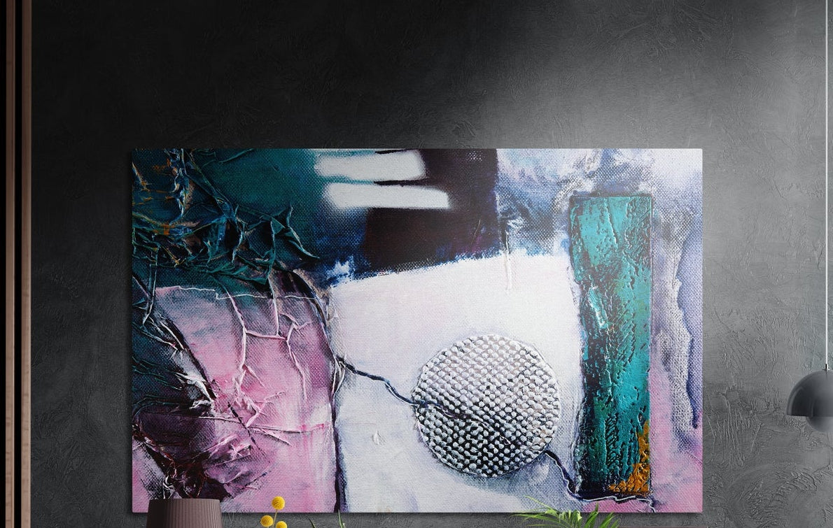 Pink and teal abstract with a silver circle, brushed aluminum wall art on a dark wall above a vase and plants