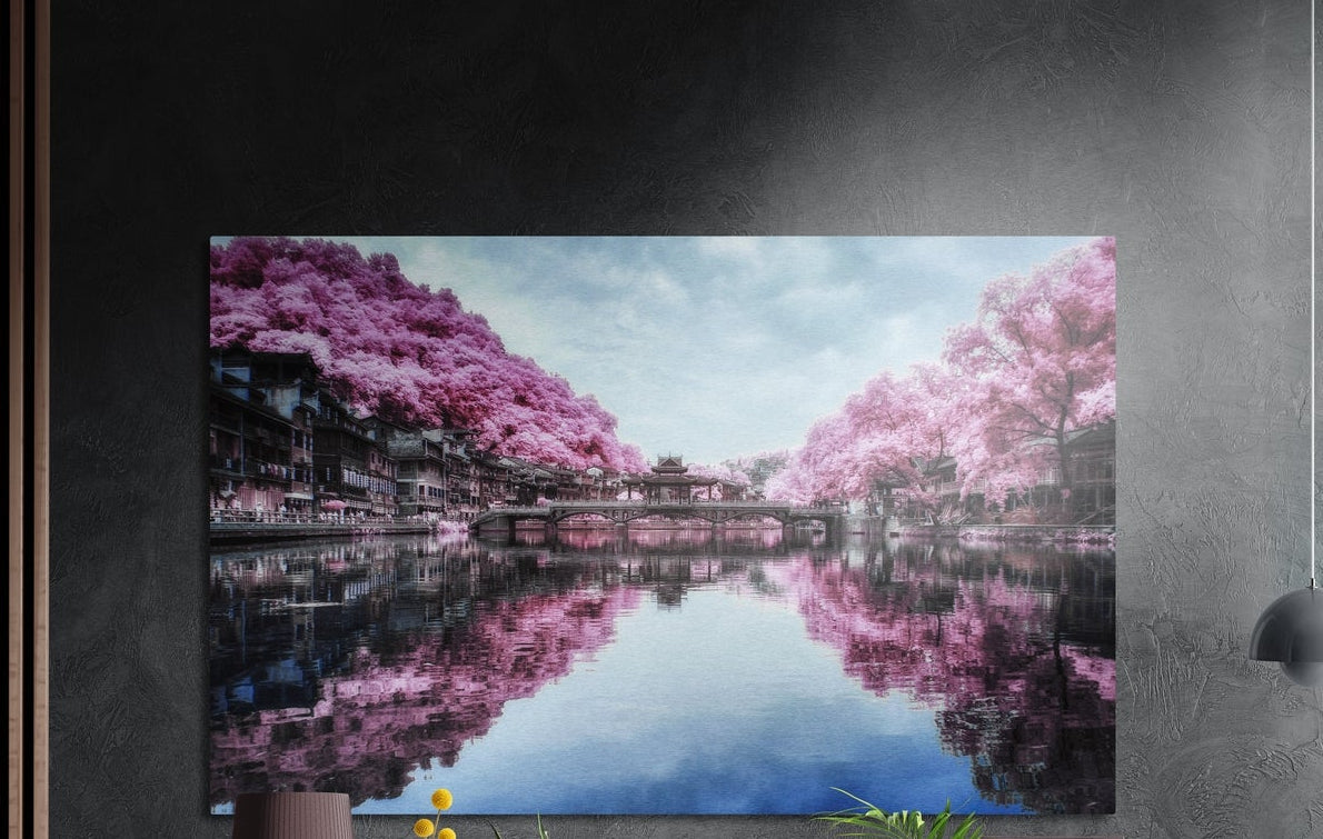 Pink blossom canal reflection brushed aluminum wall art on a dark gray wall above a mauve lamp and plants