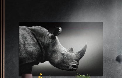 Black and white rhino in profile, brushed aluminum wall art on a gray wall above a vase and a plant