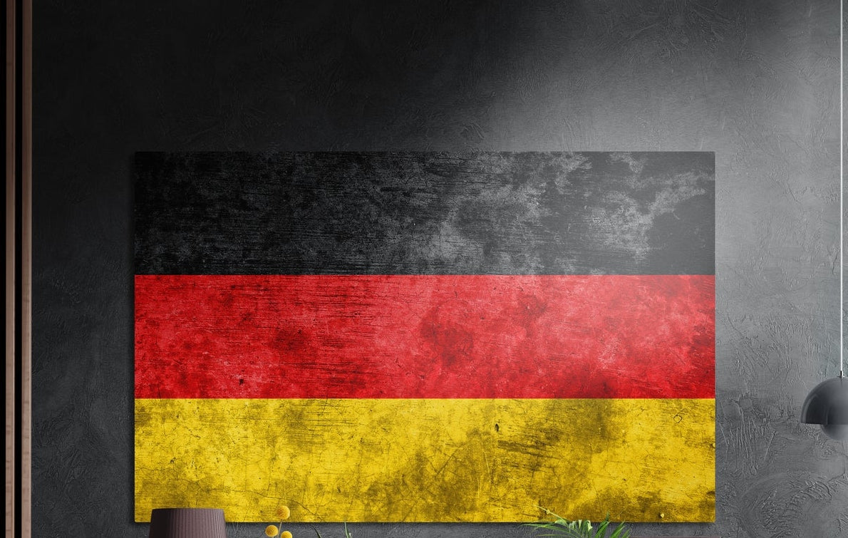 Weathered grunge Germany flag in black, red and gold bands, brushed aluminum wall art on a dark gray wall by wood slats