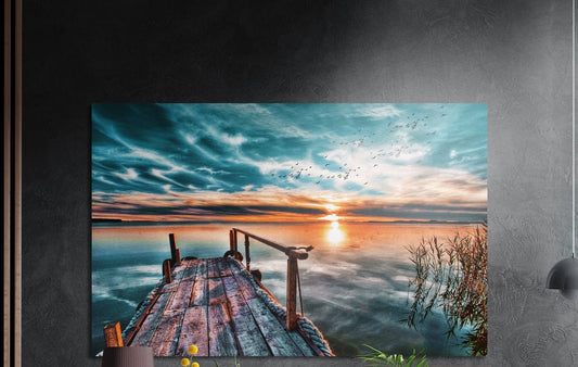 Wooden pier sunset brushed aluminum wall art on a dark gray wall above a sideboard with a vase and plants