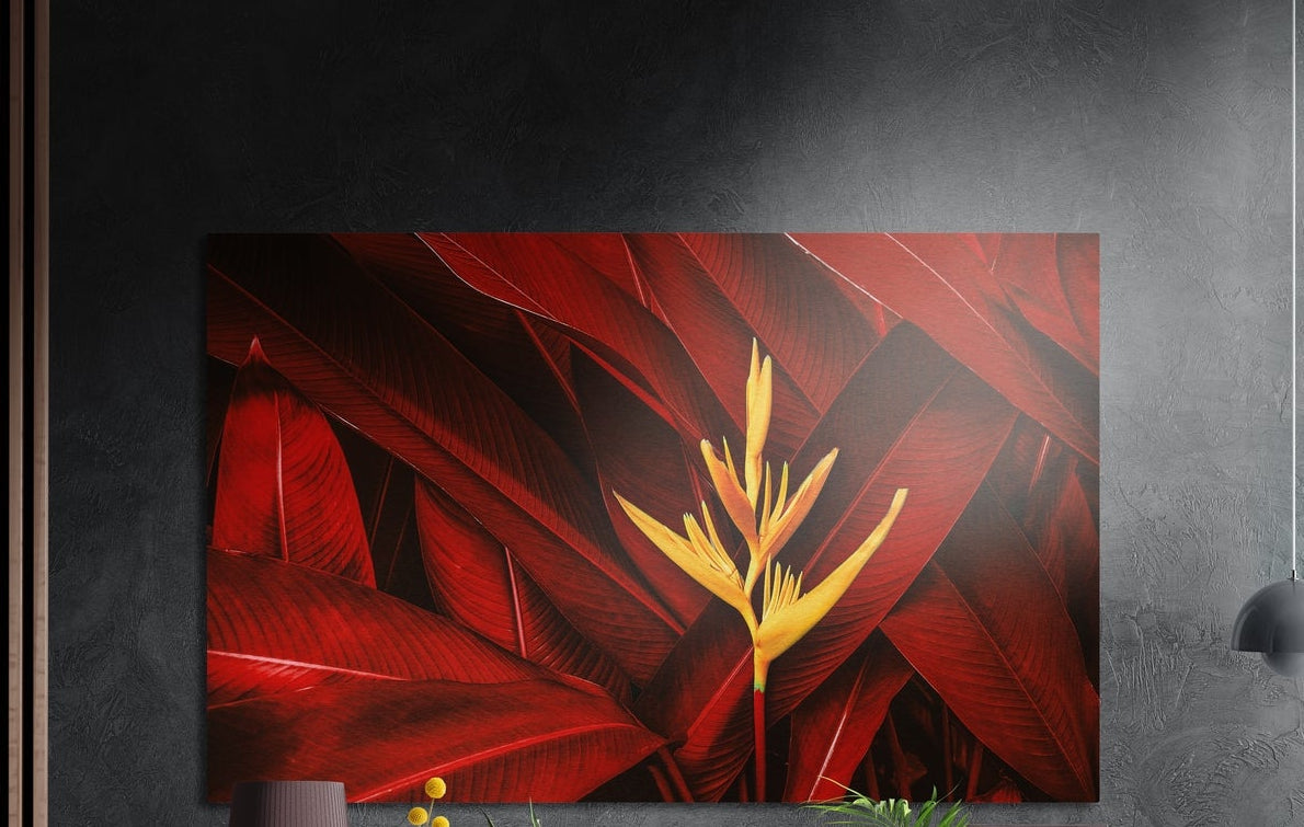 Crimson tropical leaves with a yellow bloom, brushed aluminum wall art on a dark gray wall beside a black wall lamp
