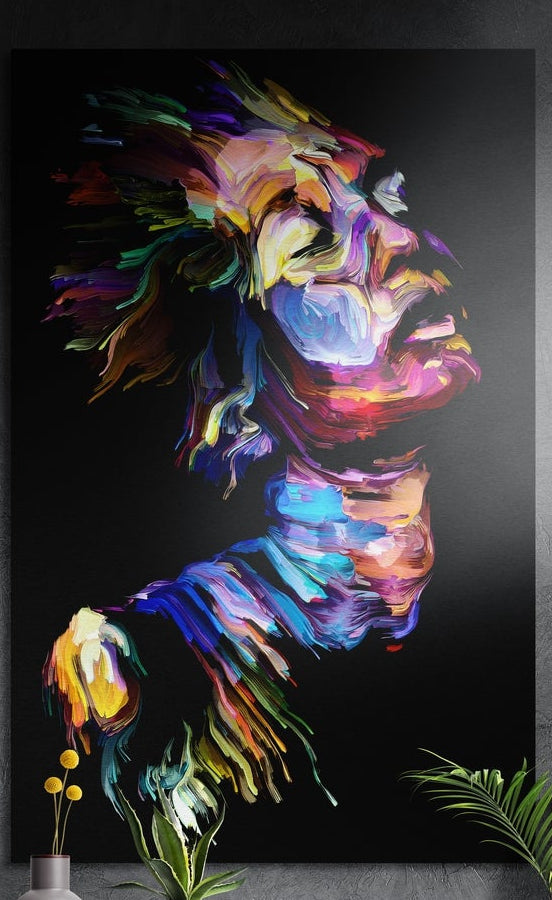 Rainbow brushstroke face in profile brushed aluminum wall art on a dark textured wall behind a vase and plants