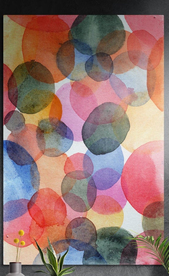 Watercolor overlapping circles brushed aluminum wall art on a dark textured wall behind a vase and plants
