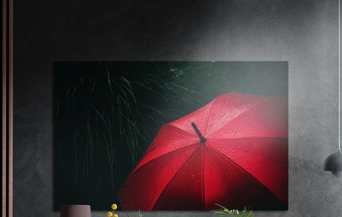 Red umbrella in the rain brushed aluminum wall art on a dark textured wall with plants below