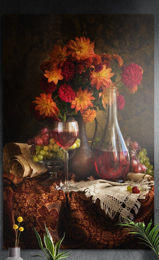 Wine and dahlias still life brushed aluminum wall art on a dark textured wall above a vase of yellow flowers and plants