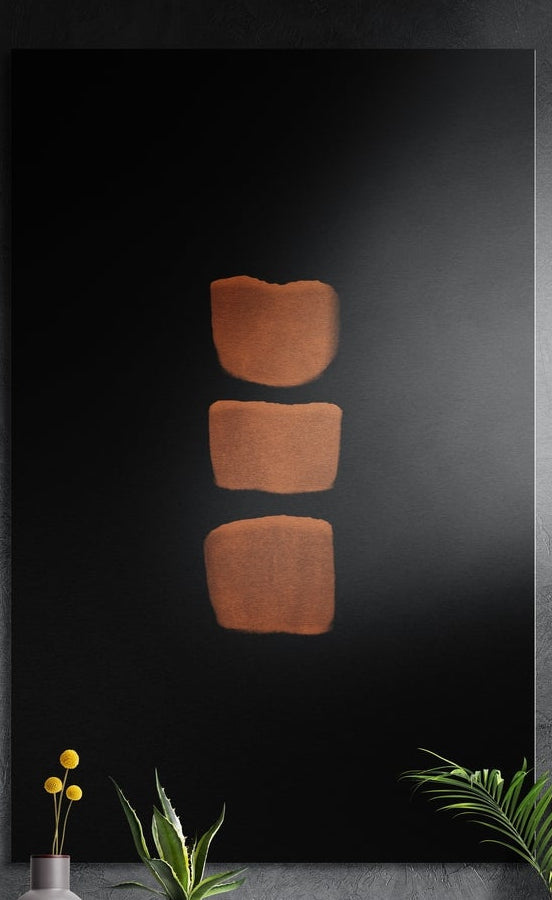 Three copper blocks stacked on black, brushed aluminum wall art on a dark gray wall above yellow flowers