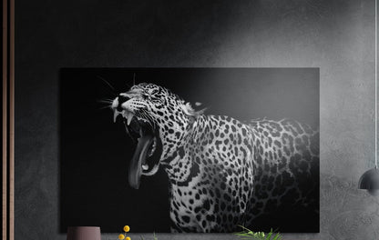 Black and white leopard with open jaws roaring toward the left on a dark background, brushed aluminum wall art on a dark wall
