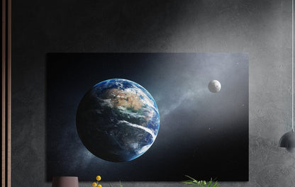 Earth and distant moon in space brushed aluminum wall art on a gray concrete wall with a lamp and plants below