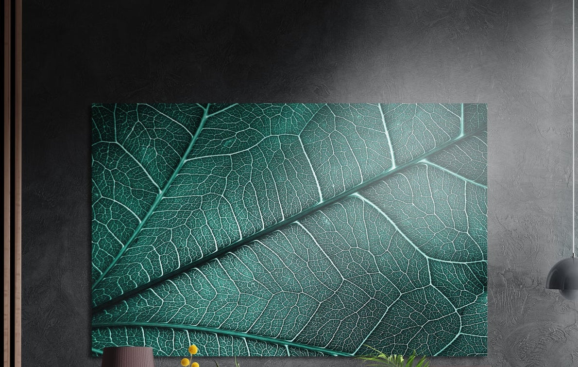Teal green leaf veins close-up, brushed aluminum wall art on a dark gray wall beside a black wall lamp