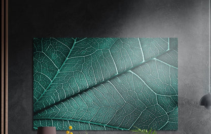 Teal green leaf veins close-up, brushed aluminum wall art on a dark gray wall beside a black wall lamp
