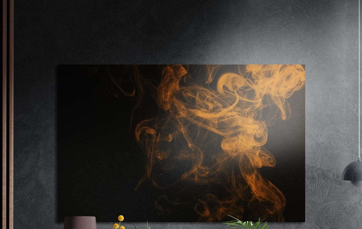 Orange smoke swirls on black brushed aluminum wall art on a dark textured wall above a vase and plants