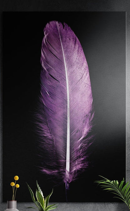 Purple feather on black brushed aluminum wall art on a dark textured wall behind a vase and plants