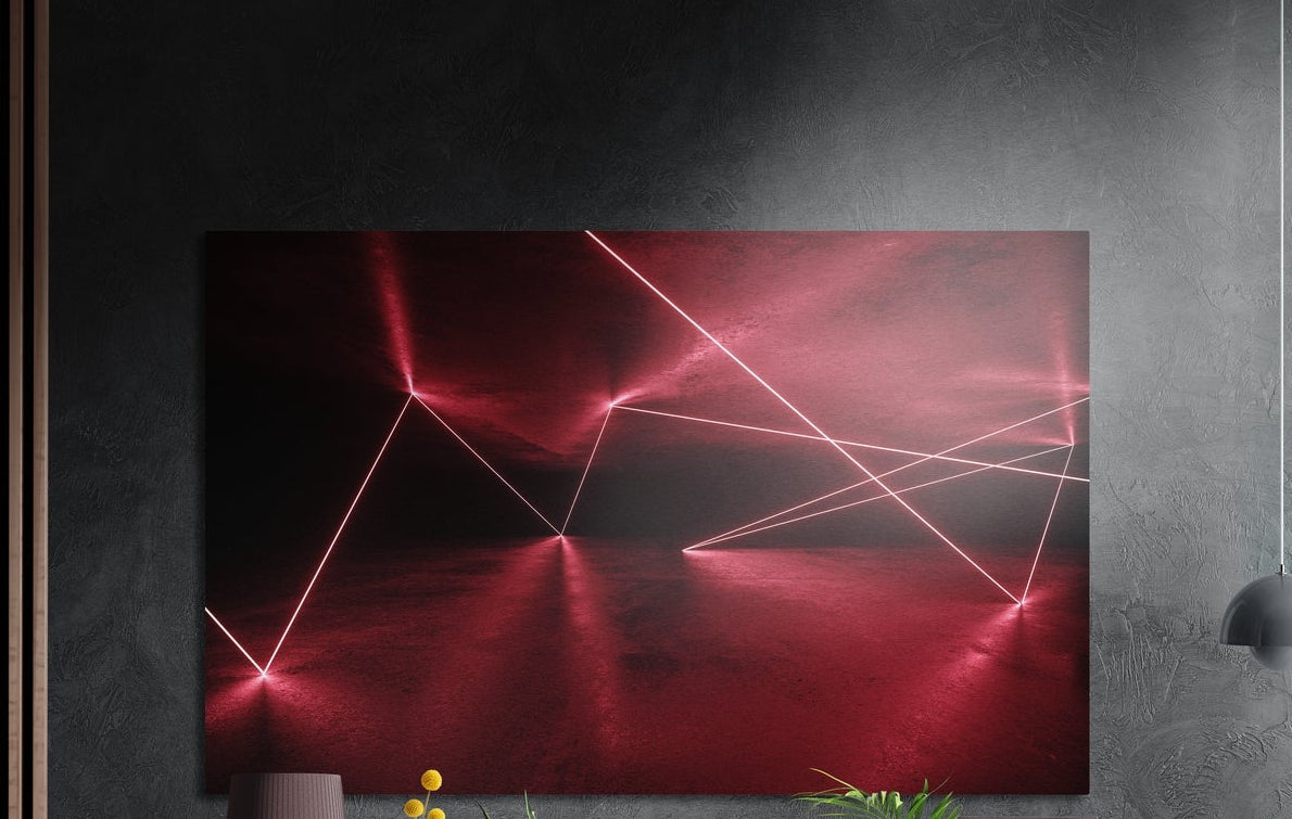 Red light lines in a dark room brushed aluminum wall art on a dark textured wall above a vase and plants