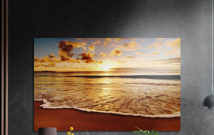 Golden beach sunset brushed aluminum wall art on a dark textured wall, foam rolling onto red sand under bright clouds