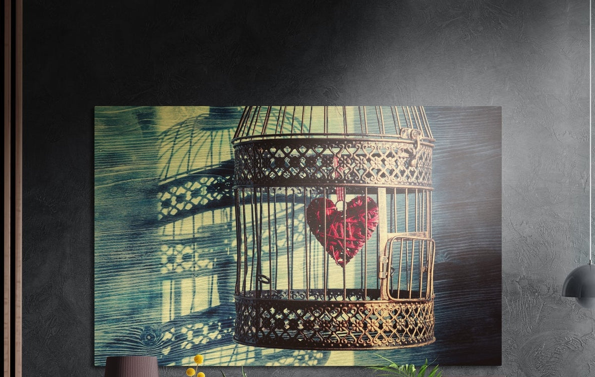 Red heart inside a golden birdcage over teal shadows, brushed aluminum wall art on a dark textured wall