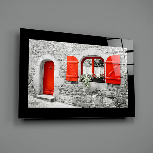 Stone cottage with a red door glass wall art on a gray wall