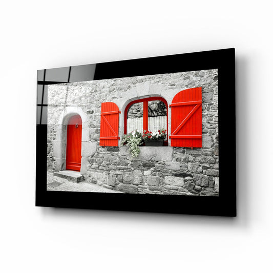 Red door and red shutters on a gray stone cottage wall, glass wall art with a black border on a white background