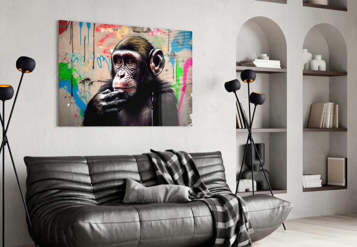 Thinking chimpanzee with headphones glass wall art above a black leather sofa beside arched white shelves