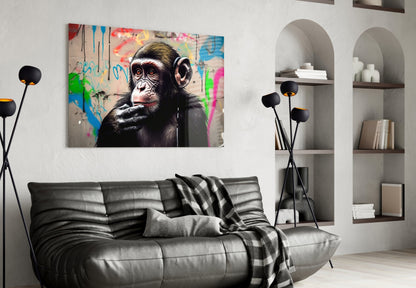 Thinking chimpanzee with headphones glass wall art above a black leather sofa beside arched white shelves