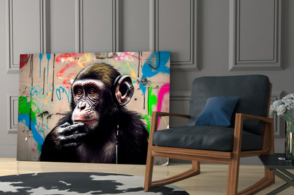 Thinking chimpanzee with headphones glass wall art leaning behind a blue armchair on a cowhide rug