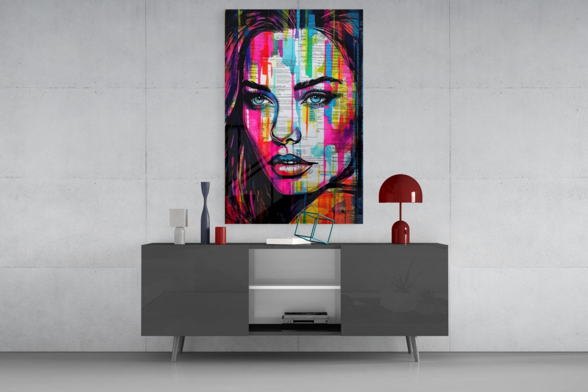 Newsprint drip woman glass wall art above a gray sideboard with a small table lamp on a white wall
