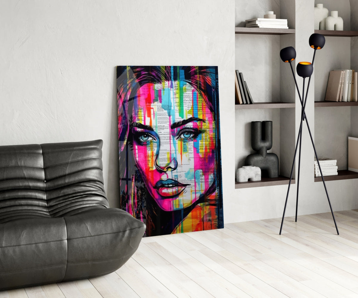 Newsprint drip woman glass wall art leaning by a black leather lounge chair and white shelves