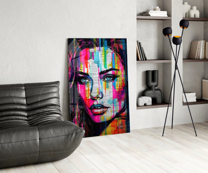 Newsprint drip woman glass wall art leaning by a black leather lounge chair and white shelves