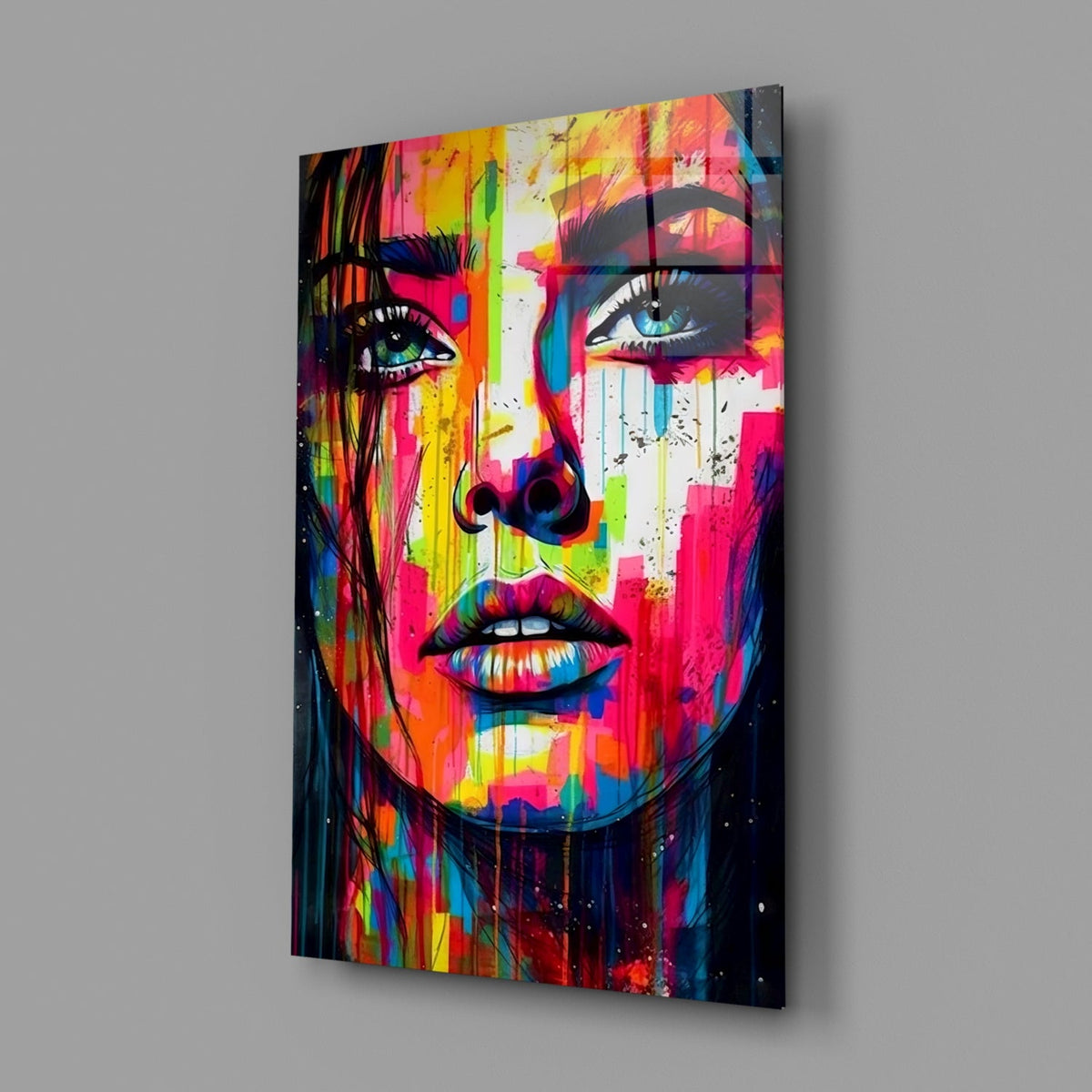 Rainbow paint drip woman face glass wall art on a gray wall, angled view