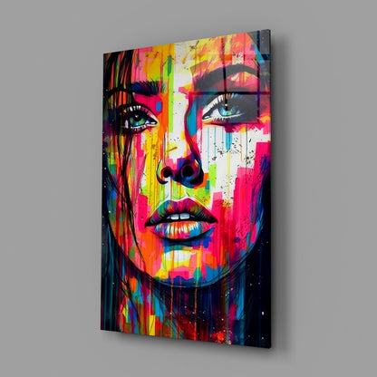 Rainbow paint drip woman face glass wall art on a gray wall, angled view