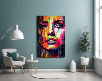 Rainbow paint drip woman face glass wall art on a teal wall above a white armchair and side table