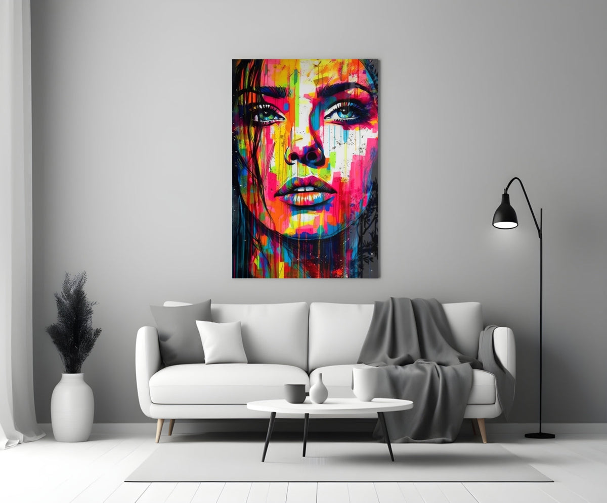 Rainbow paint drip woman face glass wall art above a white sofa and coffee table in a gray living room