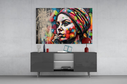 Woman in a polka dot turban glass wall art above a gray sideboard with a red lamp on a concrete wall