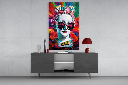 White bust in sunglasses glass wall art above a gray sideboard with a red lamp on a concrete wall
