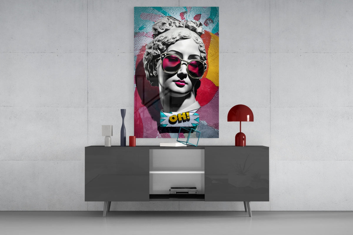 Marble bust in pink sunglasses on teal collage glass wall art above a gray sideboard with a red table lamp on a concrete wall