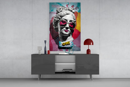 Marble bust in pink sunglasses on teal collage glass wall art above a gray sideboard with a red table lamp on a concrete wall