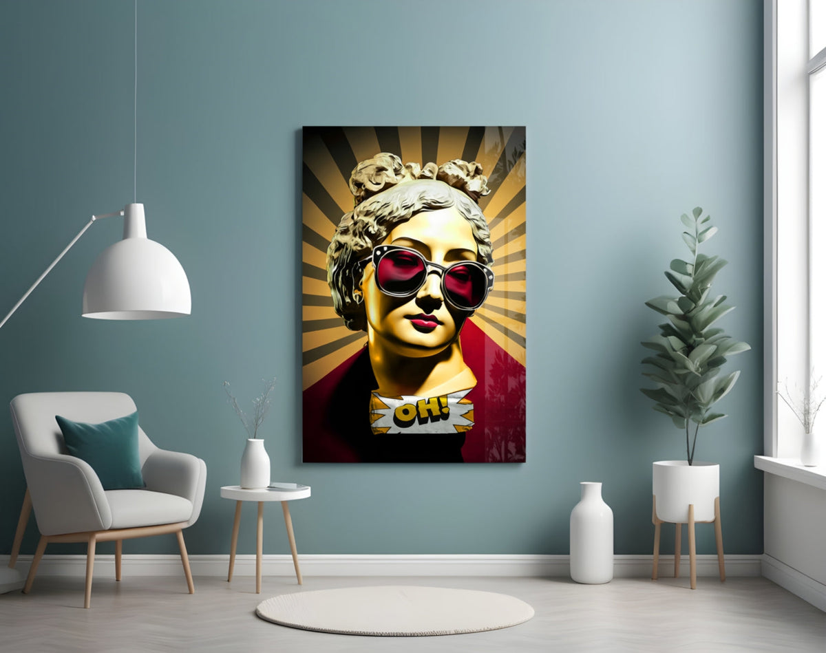 Gold bust in sunglasses on sunburst rays glass wall art on a blue-gray wall above a white armchair and a pendant lamp