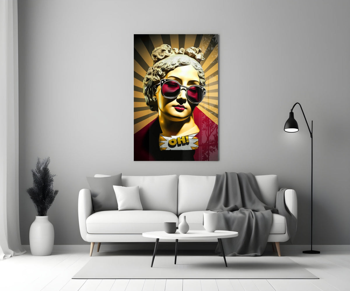 Gold bust in sunglasses on sunburst rays glass wall art above a white sofa and coffee table beside a black floor lamp