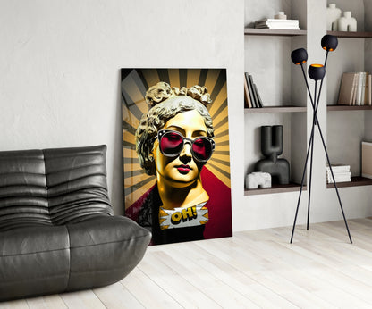Gold bust in sunglasses on sunburst rays glass wall art leaning beside a black leather lounge chair and open shelves