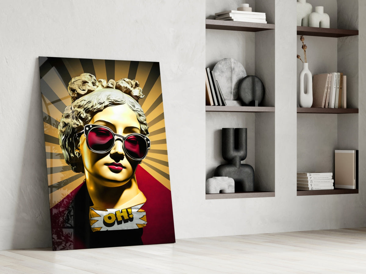 Gold bust in sunglasses on sunburst rays glass wall art leaning against a white wall beside open shelves with vases