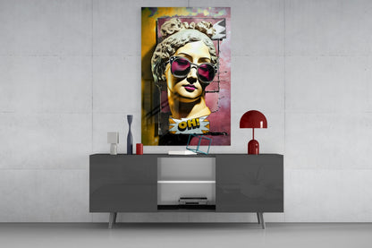 Gold bust in sunglasses on torn pink wall glass wall art above a gray sideboard with a red table lamp on a concrete wall