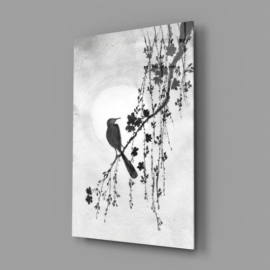 Bird on branch glass wall art on a gray wall, light reflecting off the glossy front